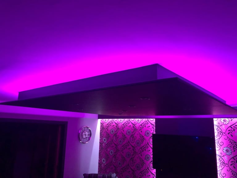 Modern interior with purple and magenta neon lighting illuminating geometric architectural features and patterned walls